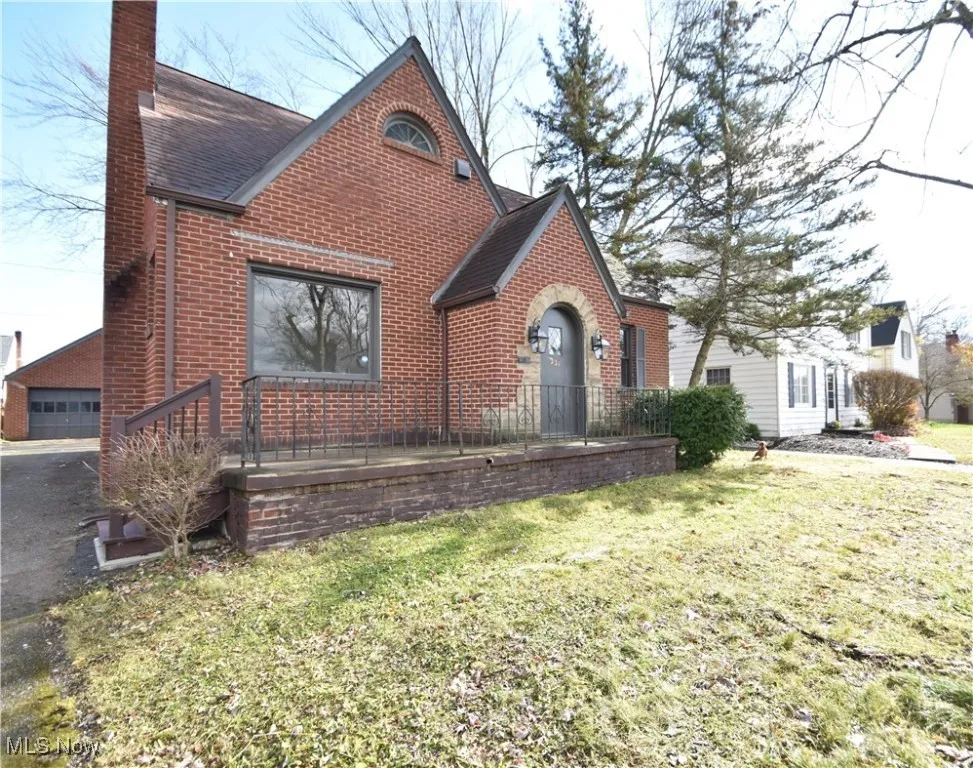Home featuring a chimney, brick siding, a front yard, roof with shingles, and a deck