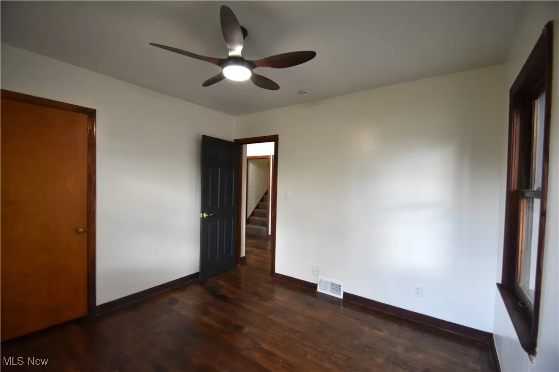 Unfurnished bedroom featuring dark wood-style flooring and ceiling fan