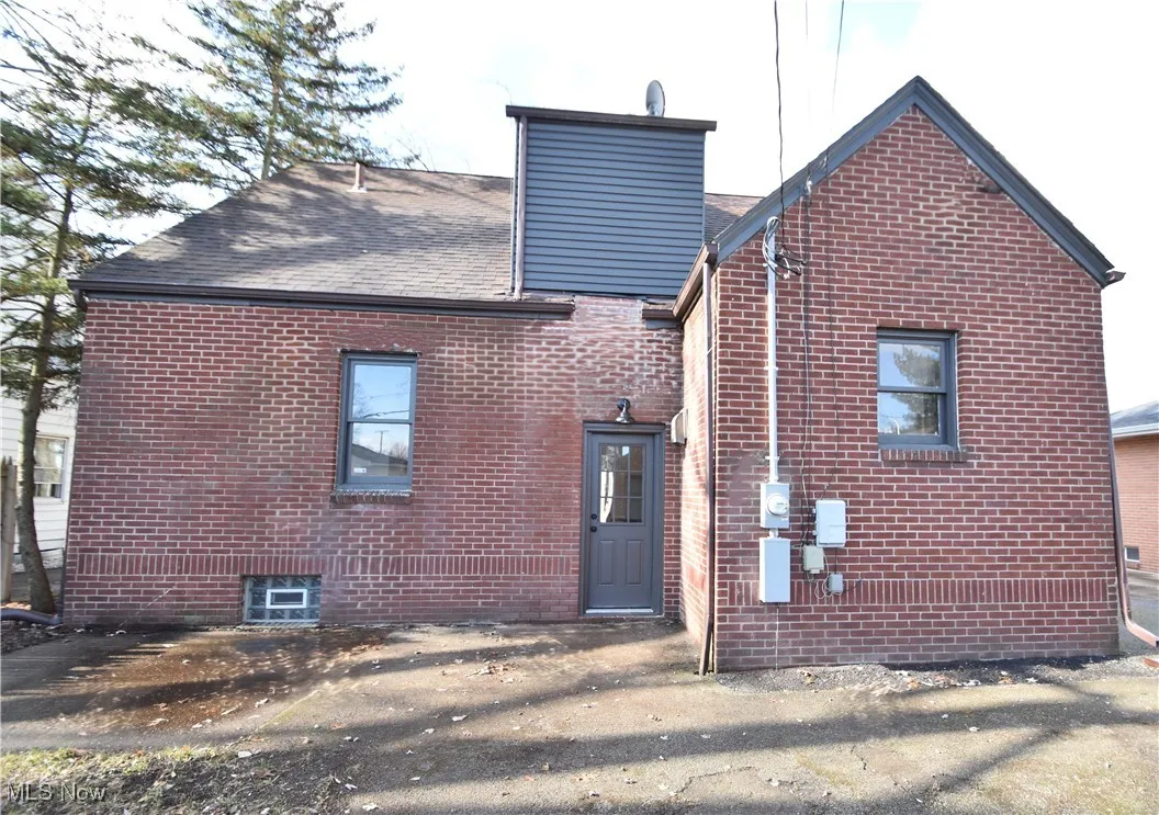 Back of house with brick siding and a shingled roof