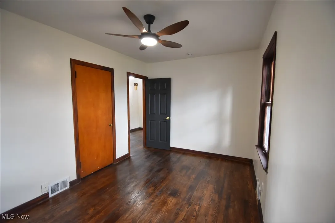 Unfurnished bedroom featuring ceiling fan and dark wood finished floors