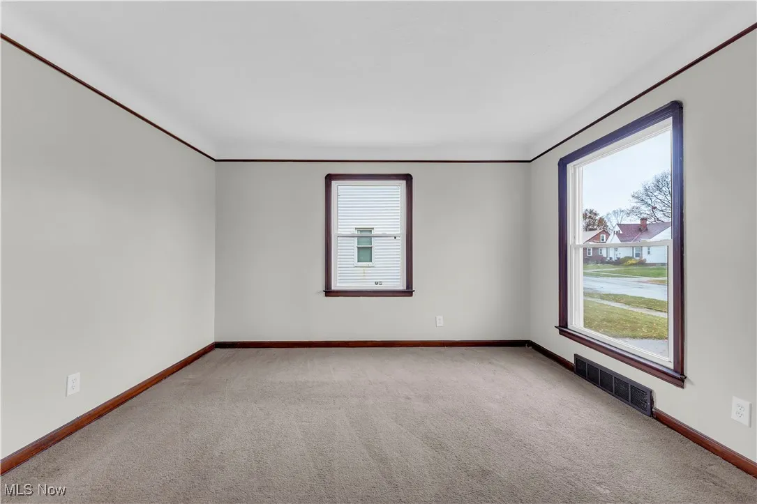 Unfurnished room featuring light carpet and baseboards