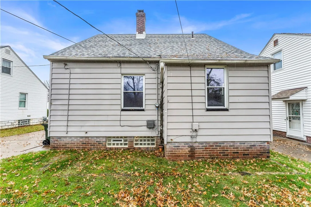 Back of property with a chimney, a yard, roof with shingles, and a patio