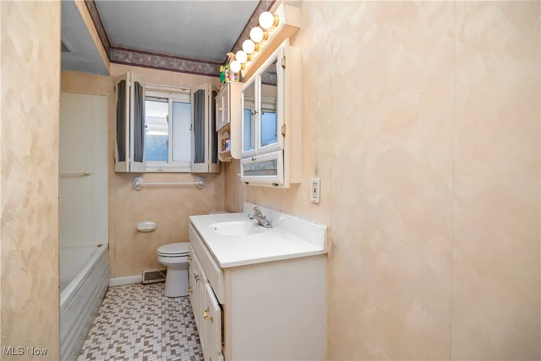 Full bathroom with vanity, light floors, and shower / bathtub combination with curtain