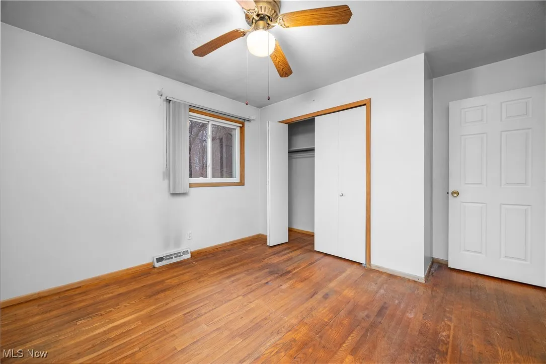 Unfurnished bedroom with hardwood / wood-style floors, a closet, and ceiling fan