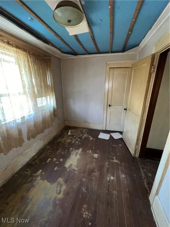 Unfurnished bedroom with baseboards and dark wood finished floors