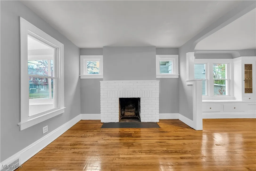 Unfurnished living room with a brick fireplace, hardwood / wood-style floors, and healthy amount of natural light