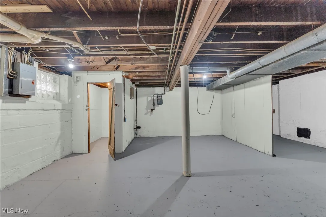 Unfinished basement featuring electric panel and gas meter
