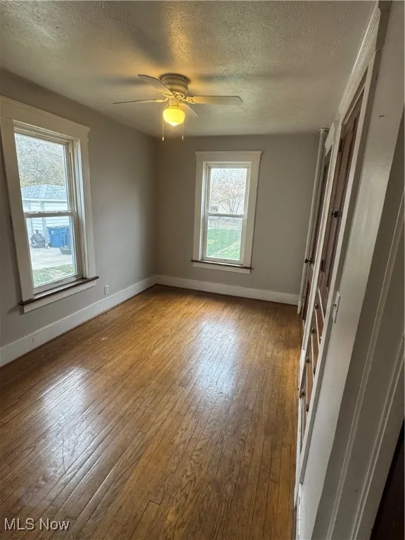 Spare room featuring a textured ceiling, wood-type flooring, and a ceiling fan