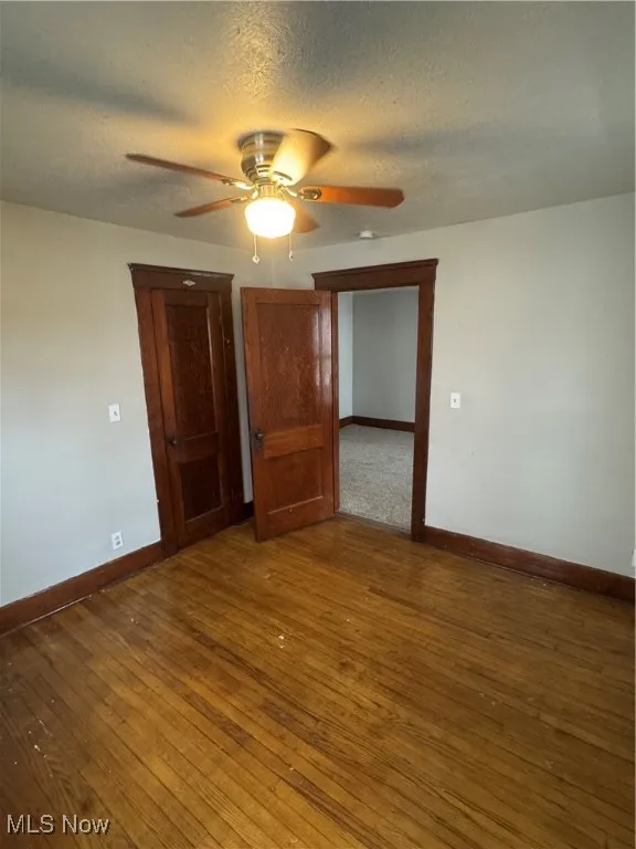 Spare room with a textured ceiling, dark wood-style floors, and a ceiling fan