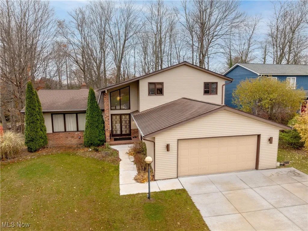 View of front of property featuring a garage, concrete driveway, a front yard, french doors, and brick siding