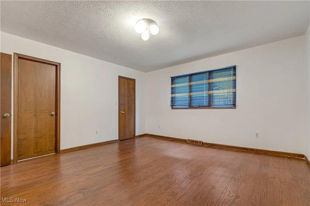 Unfurnished bedroom with a textured ceiling, wood finished floors, and a closet