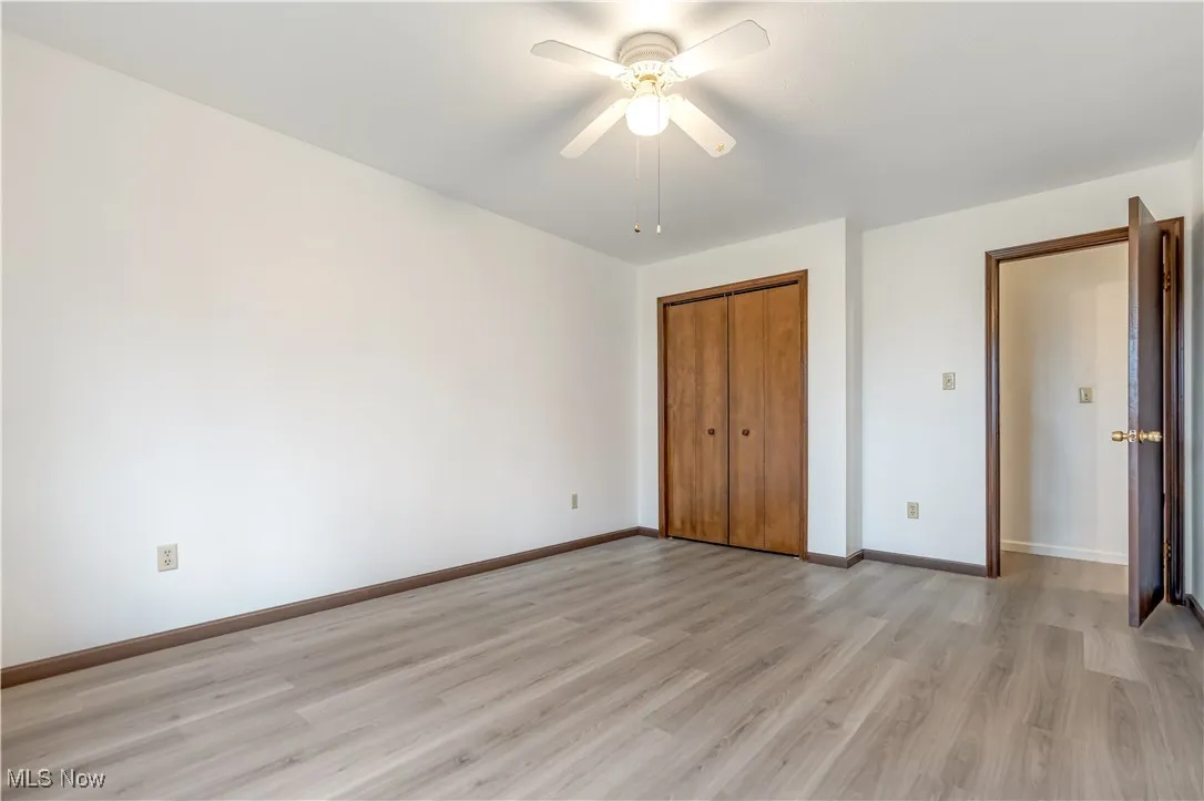 Unfurnished bedroom featuring light wood-style floors, a closet, and ceiling fan
