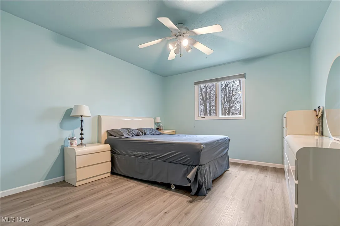 Bedroom with light wood-type flooring, ceiling fan, and a textured ceiling