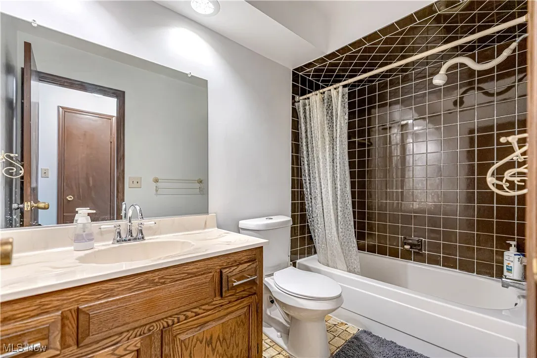 Bathroom with vanity, shower / tub combo, and light tile patterned floors