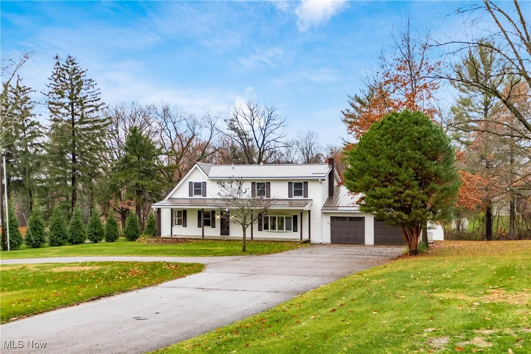 Traditional-style house featuring a metal roof, a front yard, a porch, asphalt driveway, and a standing seam roof