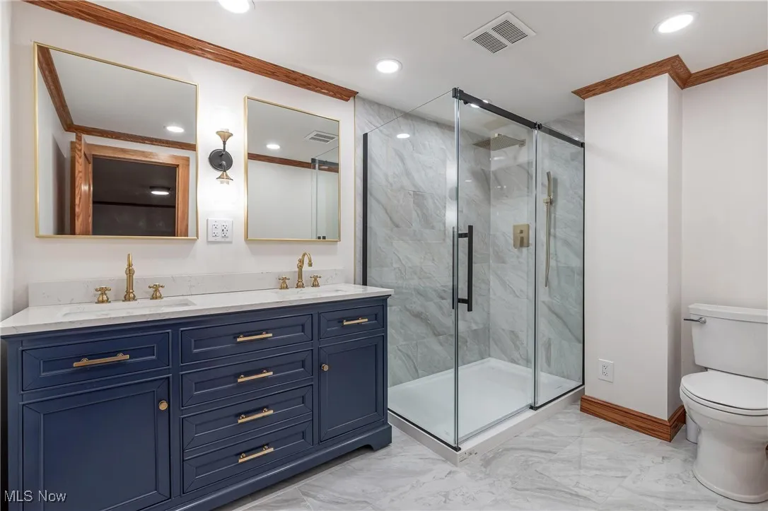 Bathroom with light marble finish floors, double vanity, recessed lighting, a marble finish shower, and crown molding