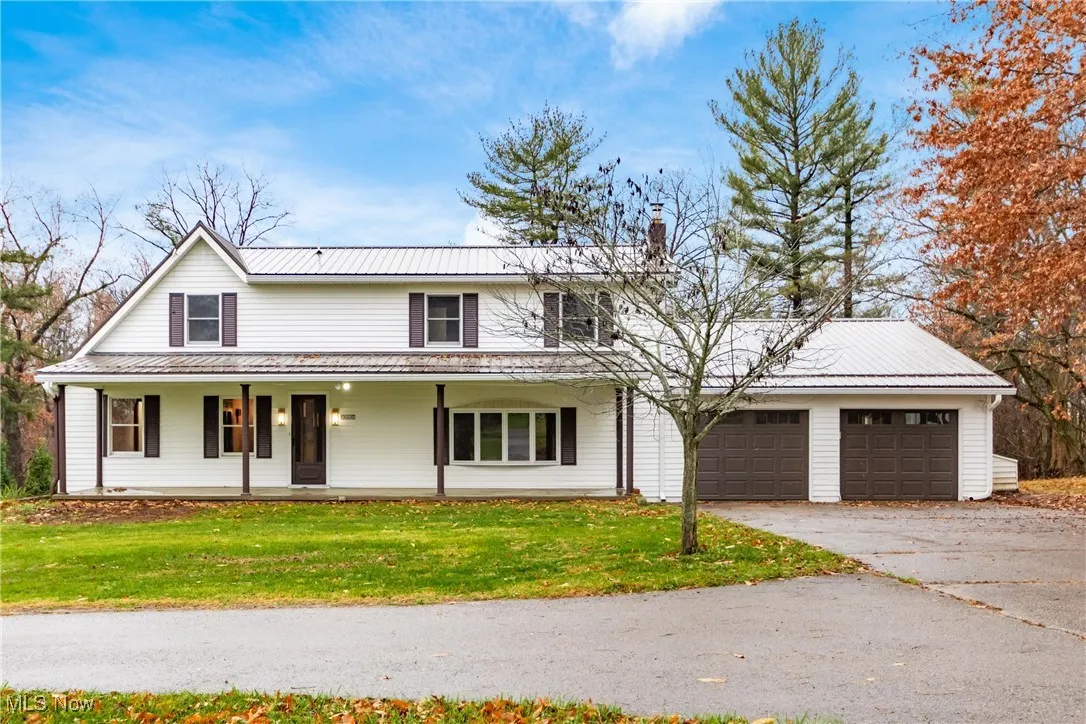 View of front facade with a front yard, a garage, covered porch, and driveway