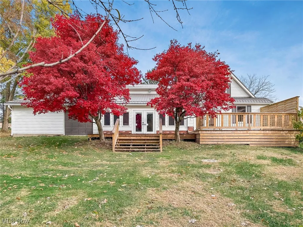 Back of property with a wooden deck, french doors, a yard, and a garage