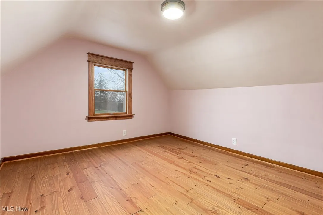 Additional living space featuring light wood finished floors and lofted ceiling