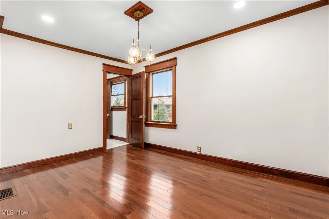 Unfurnished room featuring wood-type flooring, a chandelier, crown molding, and recessed lighting