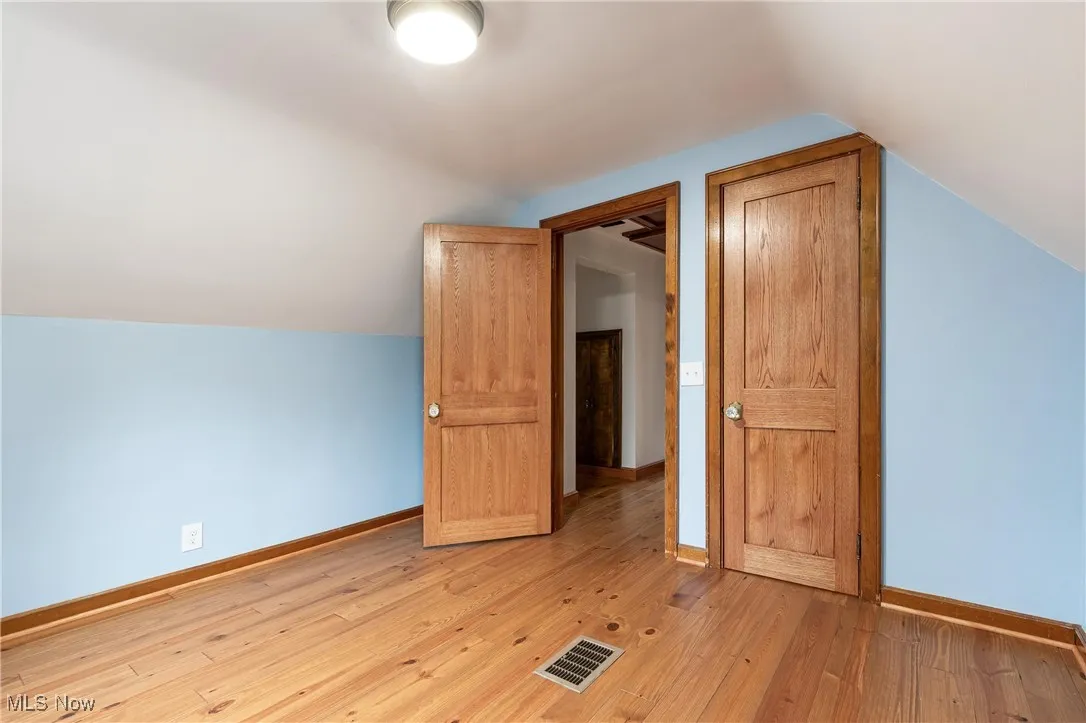 Additional living space featuring lofted ceiling and light wood-type flooring