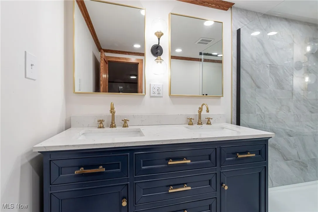 Bathroom featuring double vanity, a tile shower, and recessed lighting