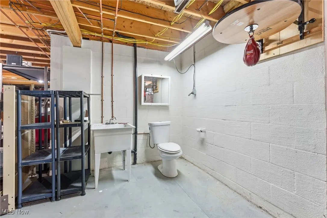Half bathroom with toilet and unfinished concrete floors