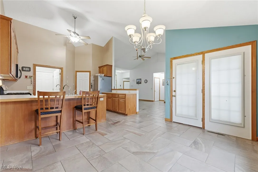 Kitchen with a peninsula, a breakfast bar area, a chandelier, brown cabinets, and pendant lighting