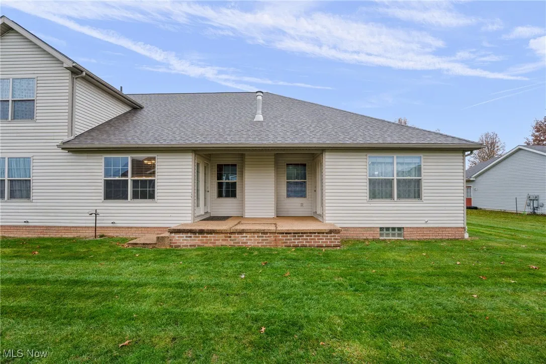 Back of house featuring roof with shingles, a patio area, and a yard