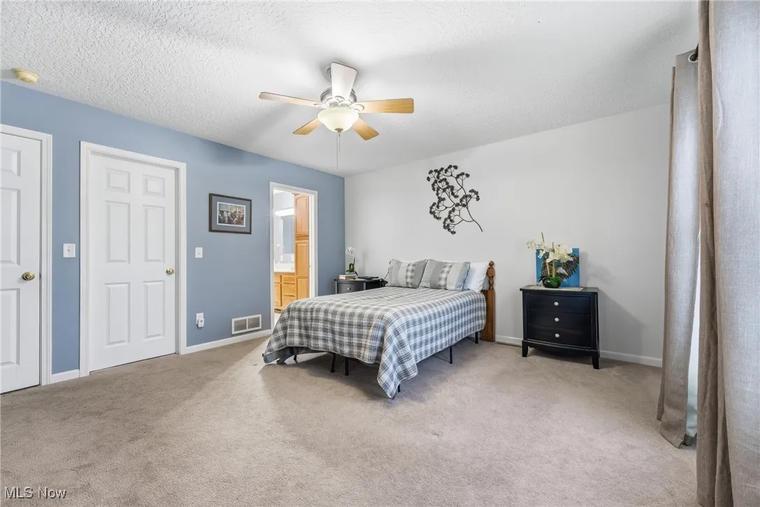Bedroom featuring carpet, ceiling fan, a textured ceiling, and ensuite bathroom