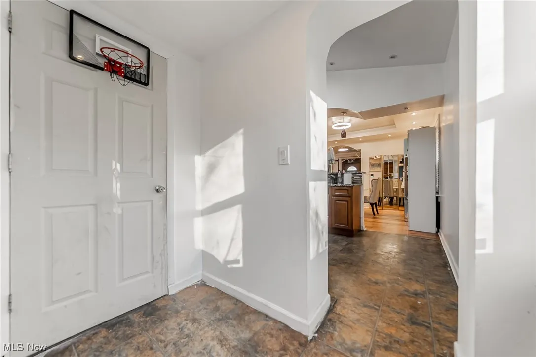 Hallway featuring arched walkways, stone finish flooring, and recessed lighting