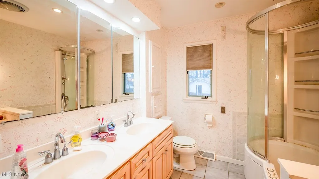 Bathroom with wallpapered walls, double vanity, light tile patterned flooring, combined bath / shower with glass door, and recessed lighting