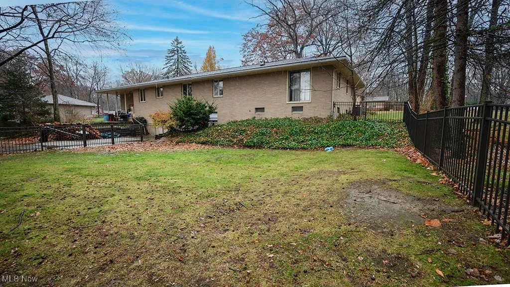 Rear view of property with a fenced backyard, brick siding, and a wooden deck