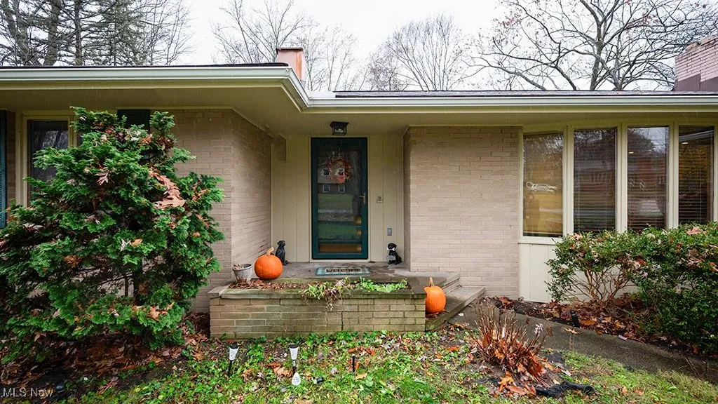 View of exterior entry with brick siding and covered porch