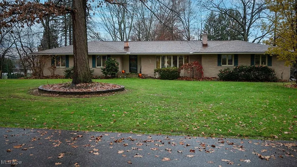 Ranch-style home with a front lawn, a chimney, and brick siding
