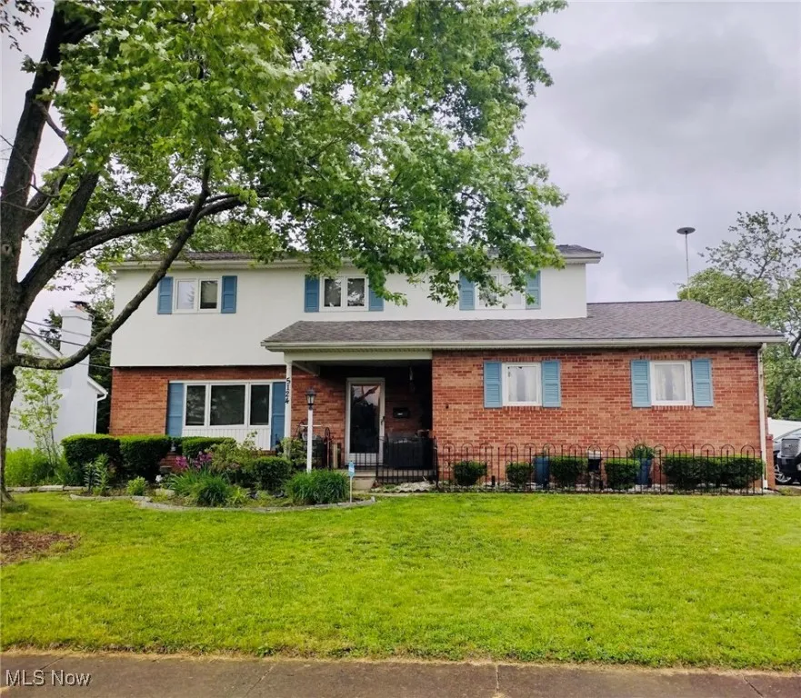 Traditional home featuring a front yard, brick siding, and a porch