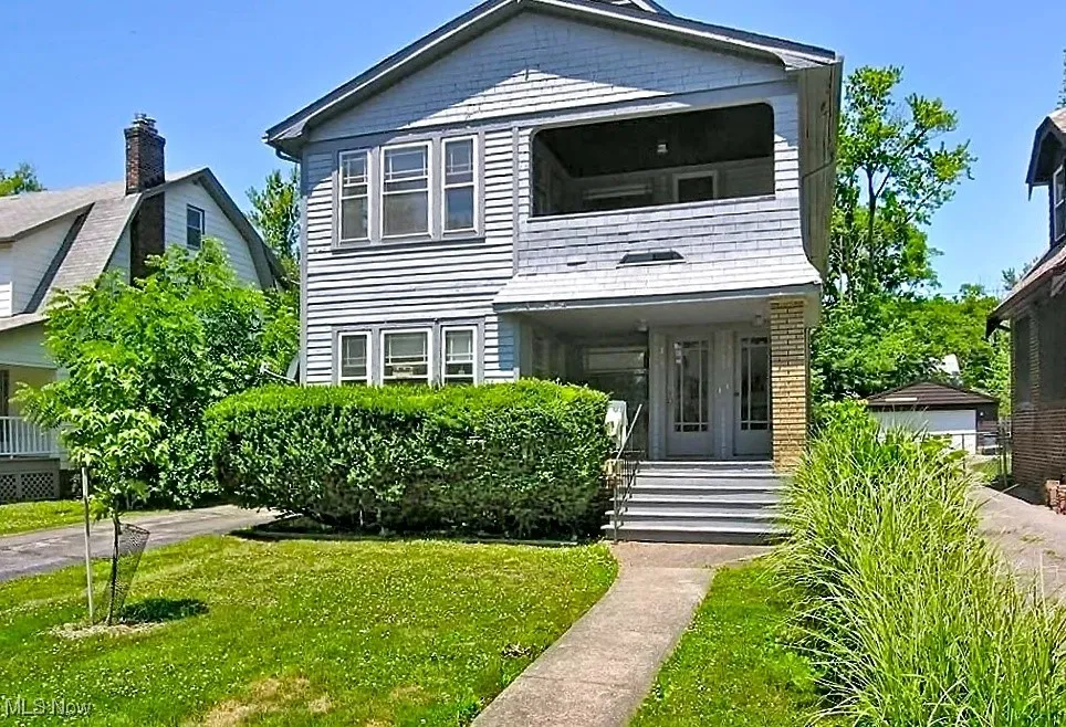View of front of property with a front yard, a balcony, and a porch