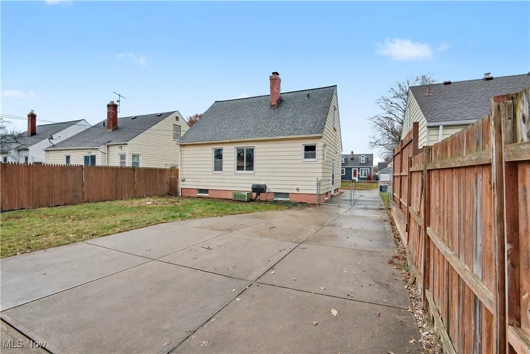 Rear view of property with a fenced backyard, a chimney, and roof with shingles
