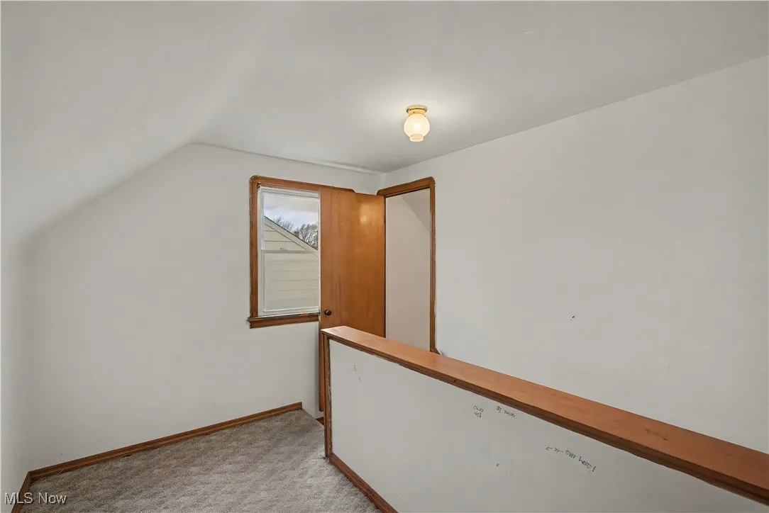 Additional living space featuring lofted ceiling and light colored carpet
