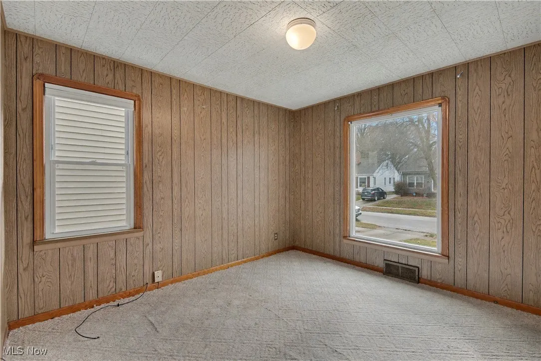 Carpeted empty room featuring wood walls