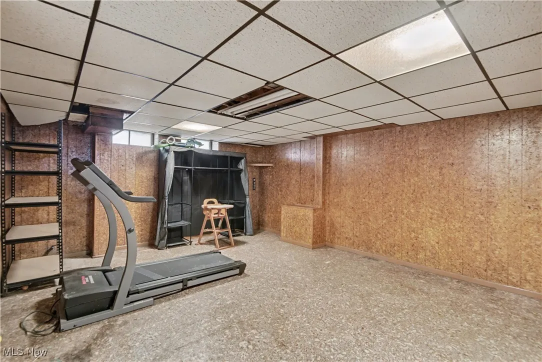 Exercise room featuring a paneled ceiling and wood walls