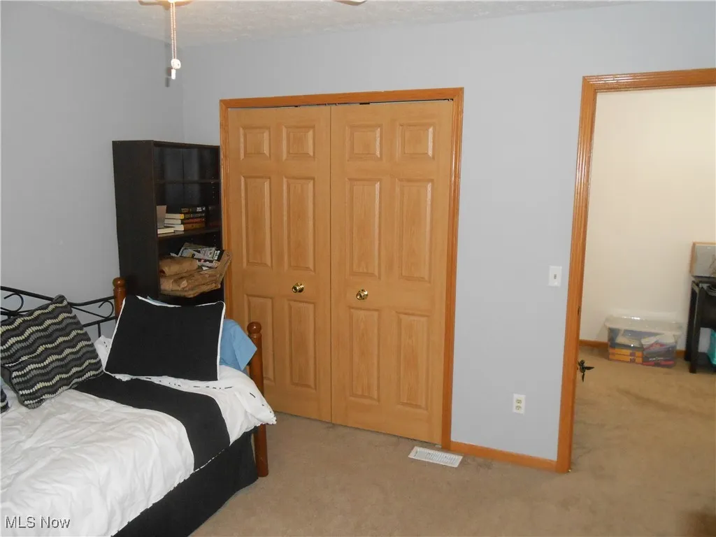 Bedroom with light colored carpet, a closet, and a textured ceiling