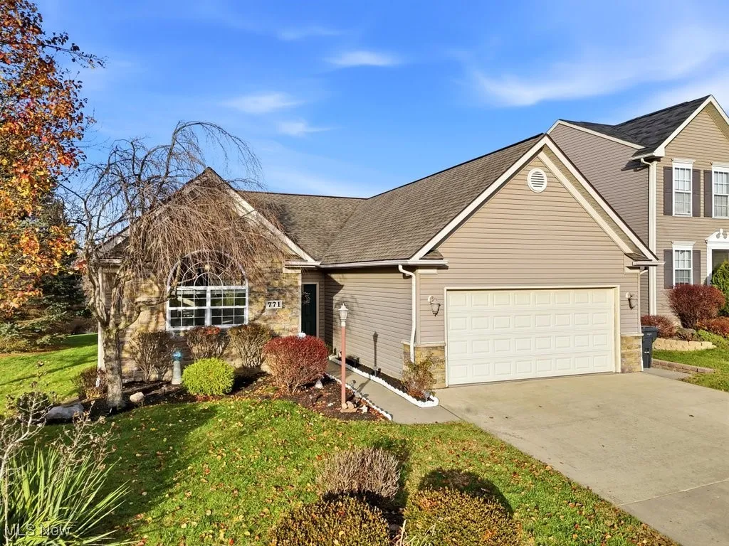 View of front of house with concrete driveway, a front yard, a shingled roof, and a garage