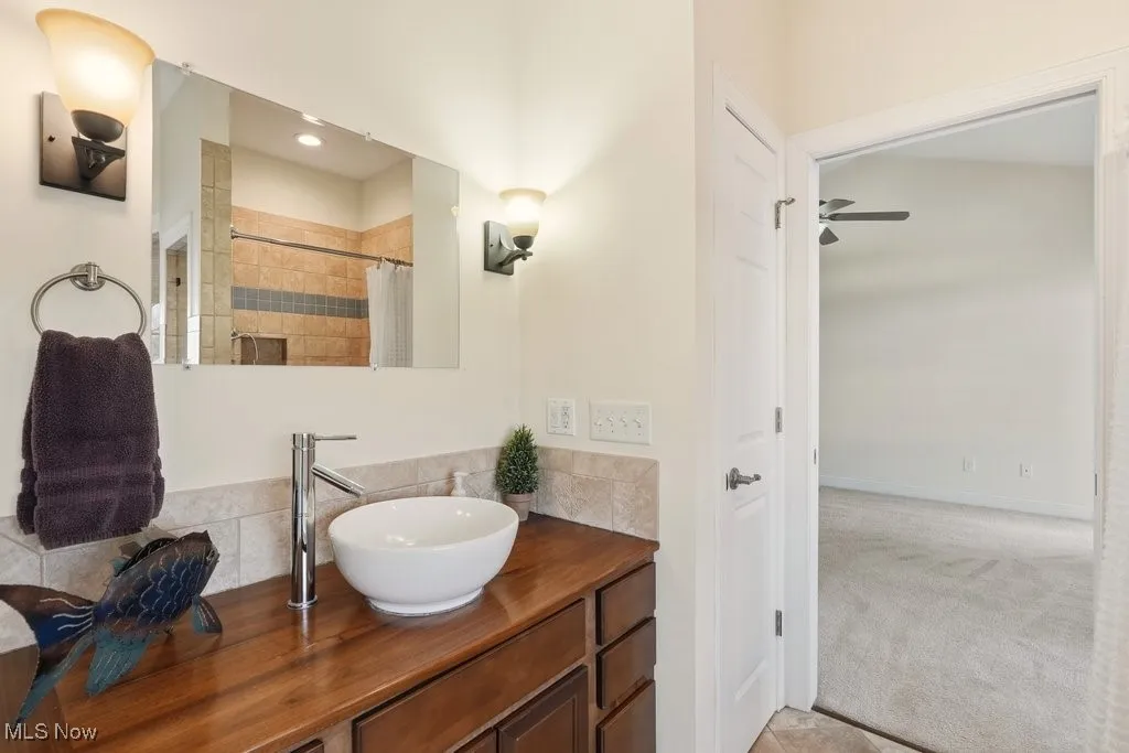 Full bathroom with a tile shower, vessel sink vanity, and linen closet