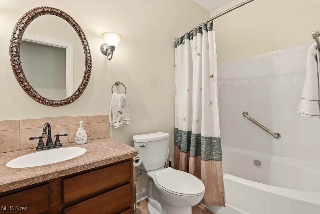 Full bath with vanity, shower / bathtub combination with curtain, and backsplash