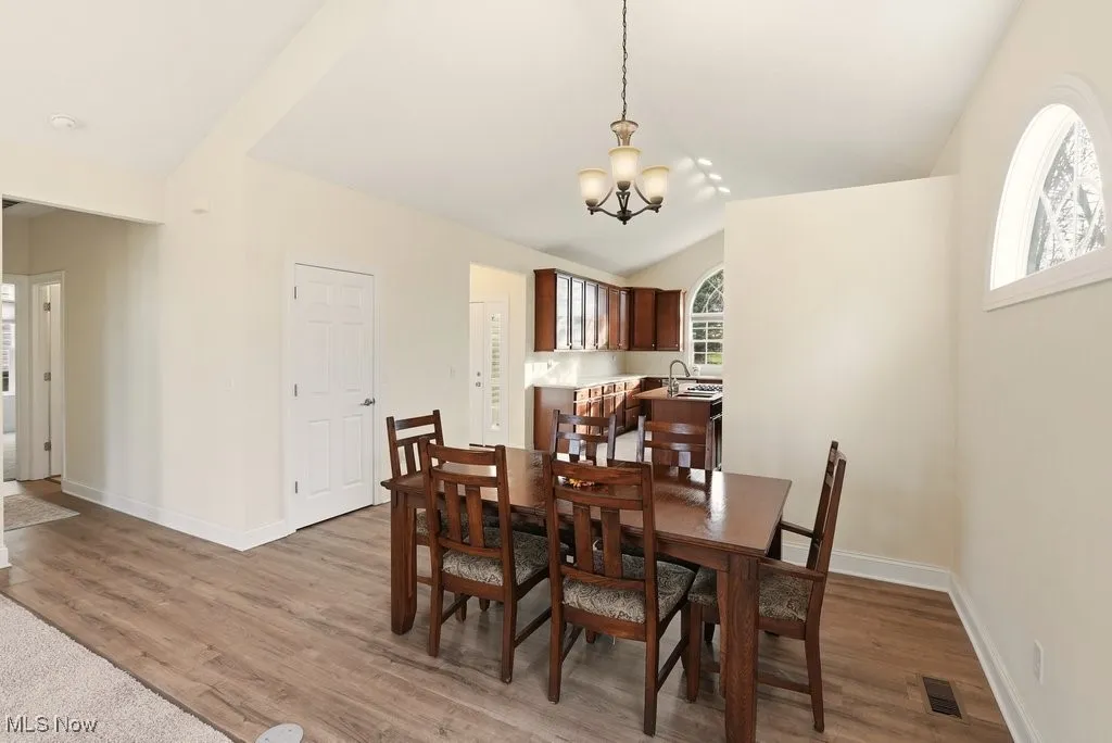 Dining space with healthy amount of natural light, a chandelier, light wood-style floors, and vaulted ceiling