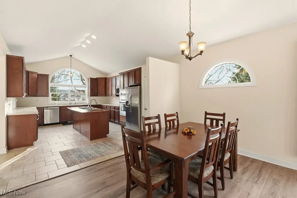 Dining area with a chandelier, vaulted ceiling, and light wood-style flooring