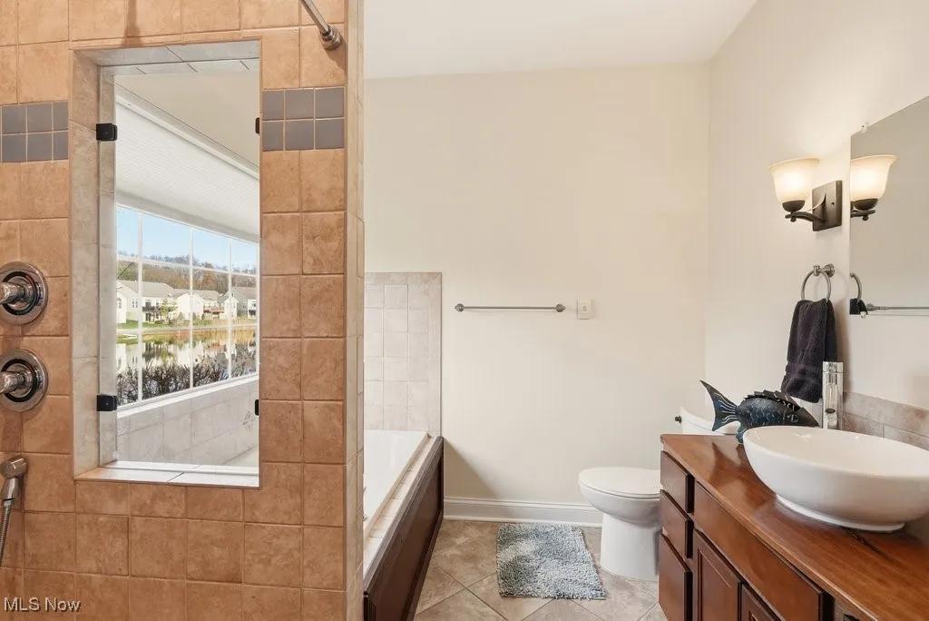 Full bath with a garden tub, vanity, tiled shower, light tile patterned flooring, and a water view