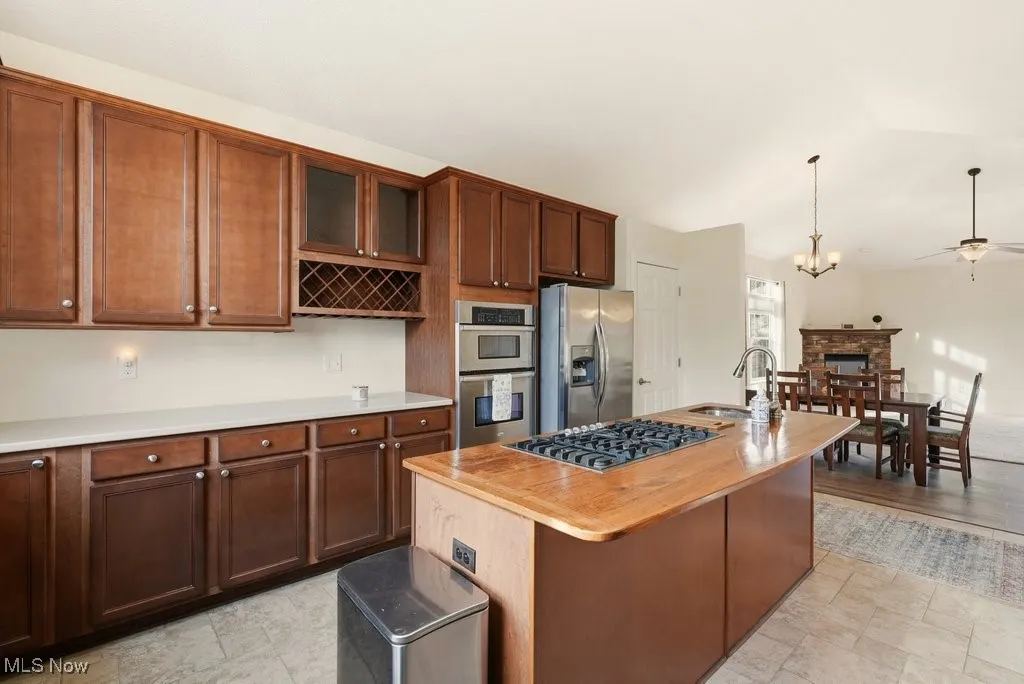Kitchen with a center island with sink, appliances with stainless steel finishes, hanging light fixtures, and vaulted ceiling