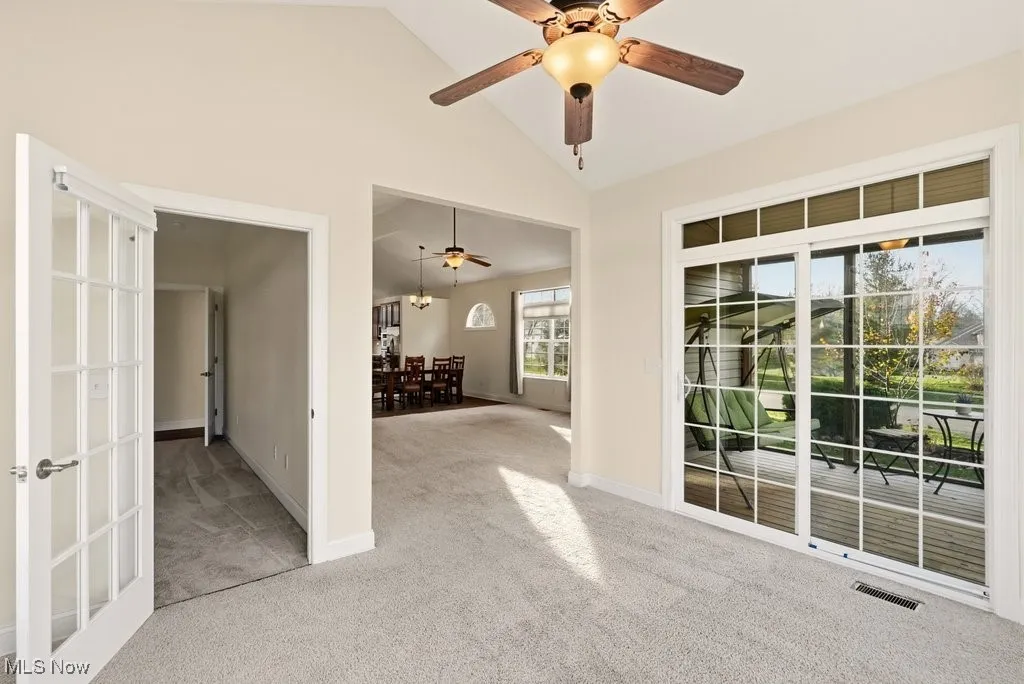 Sun room featuring vaulted ceiling, light carpet, and a ceiling fan